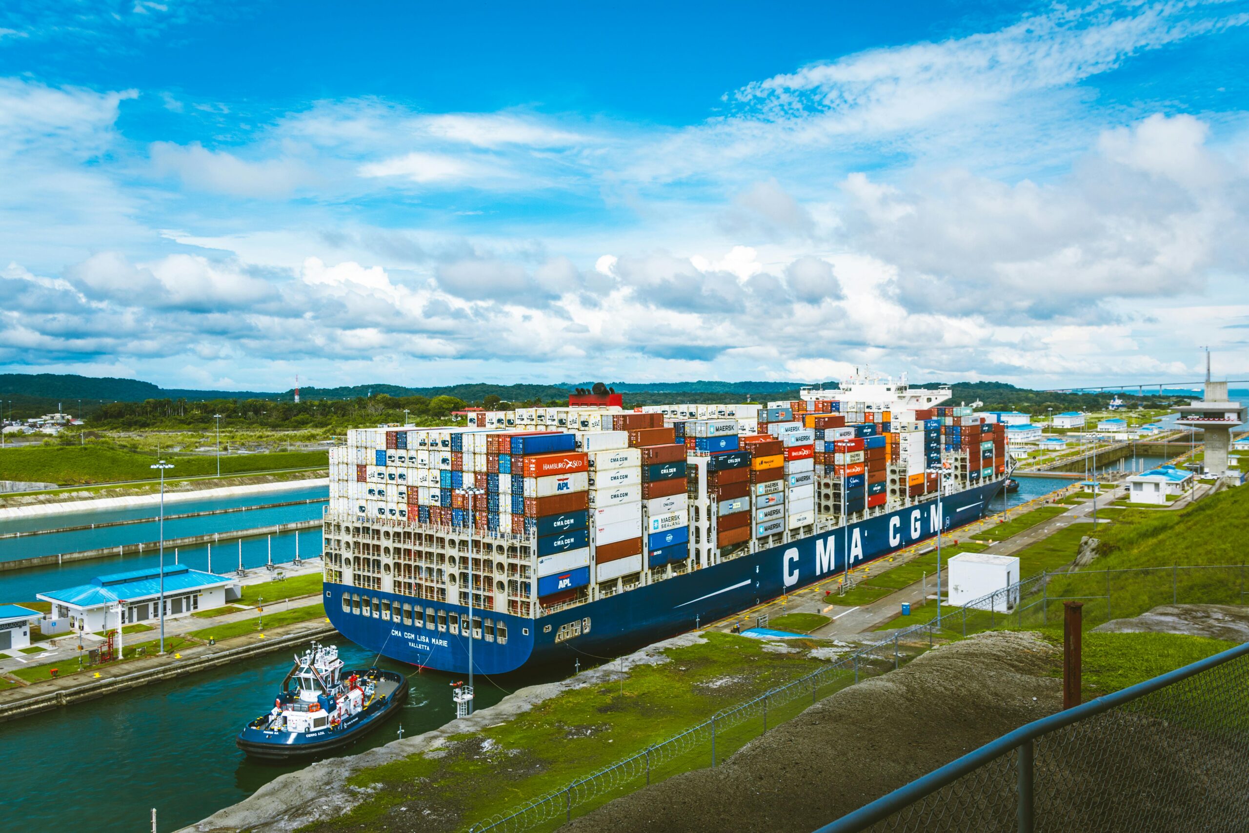A vast cargo ship passes through the Panama Canal on a bright day, showcasing global trade.